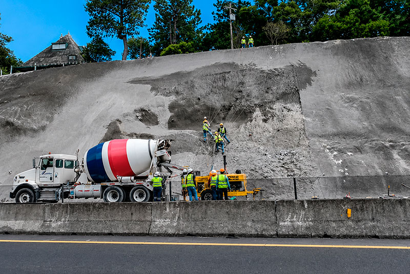 Camión bombeando concreto lanzado sobre un talud junto a la carretera