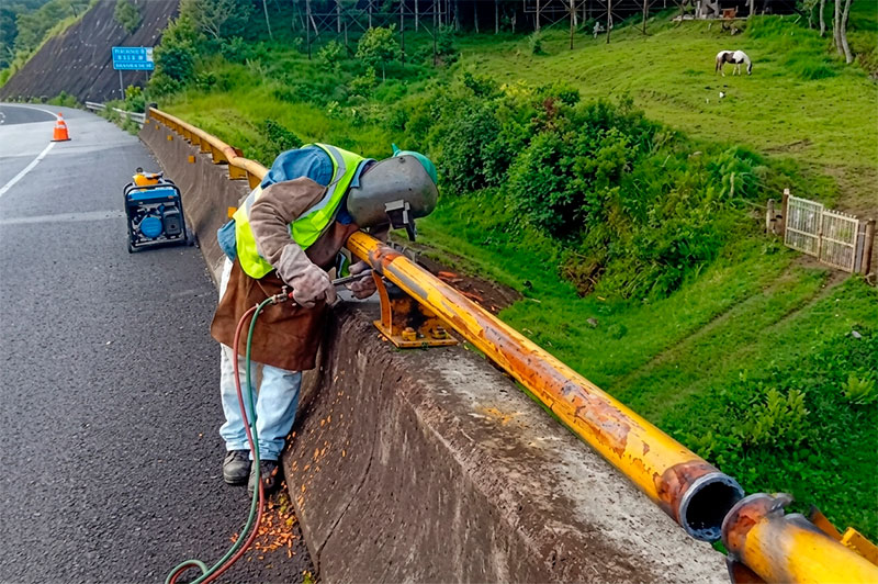 Trabajador reparando el sistema de contención metálico de la autopista