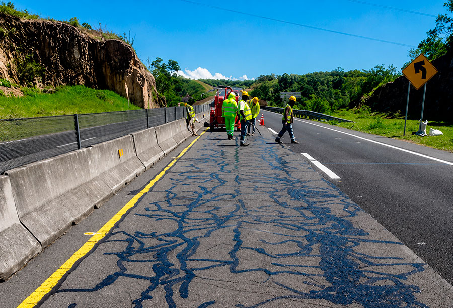 Cuadrilla aplicando sellado de grietas en el pavimento de una carretera